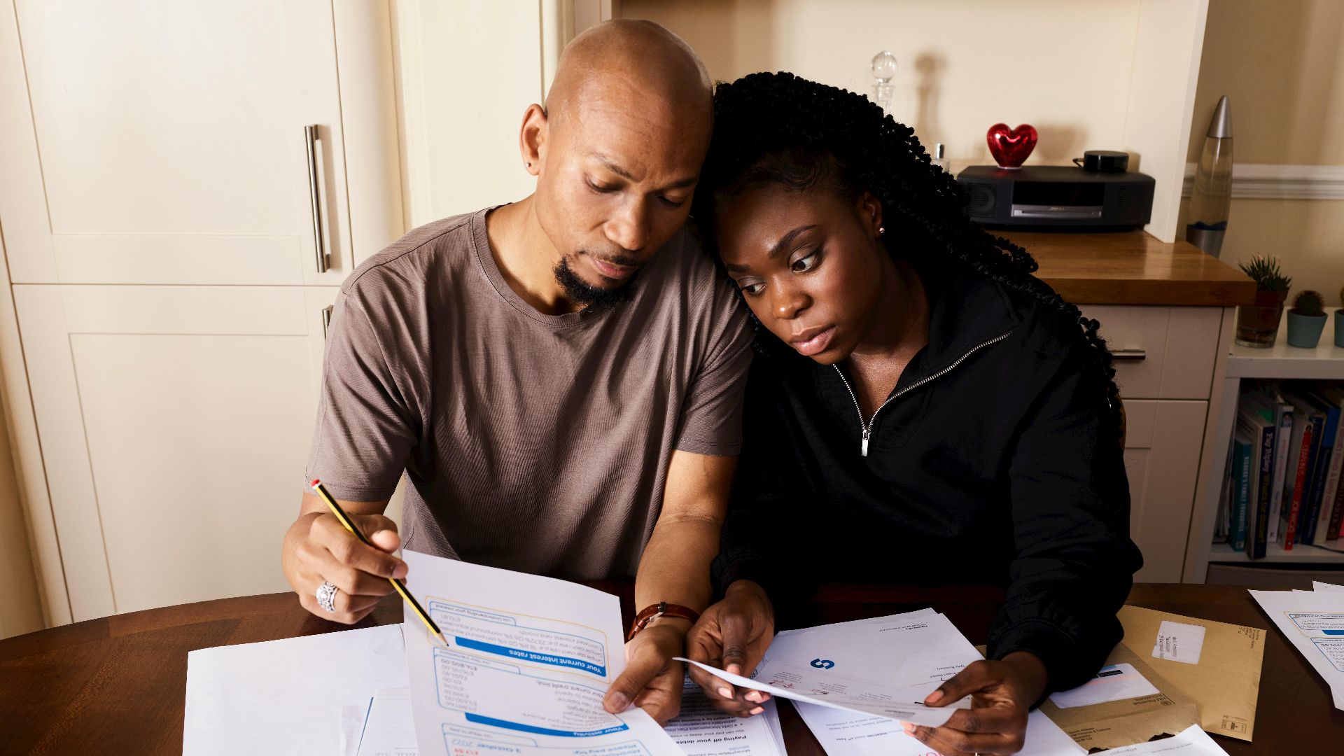 A couple sitting at a table reviewing financial documents, highlighting domestic budgeting.