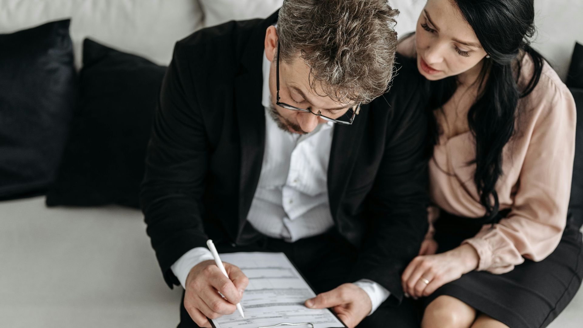An adult couple sitting together reviewing documents in a modern indoor setting.