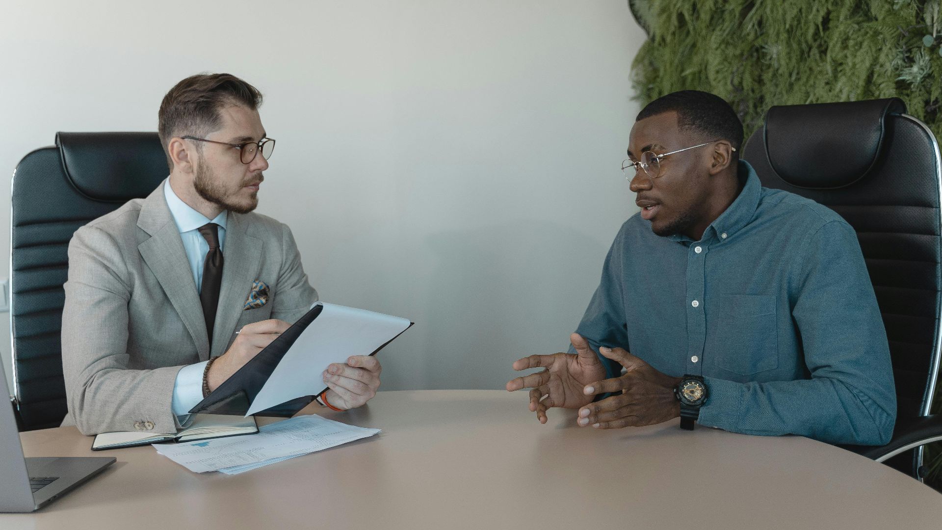 Two businessmen engaged in a discussion during a job interview in a contemporary office environment.