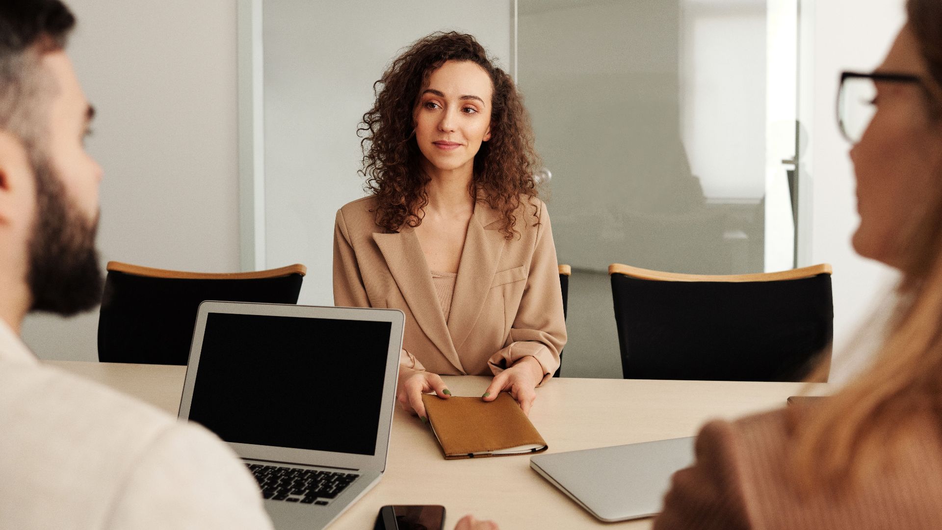 A woman in a business suit participates in a job interview, showcasing professionalism and modern office environment.