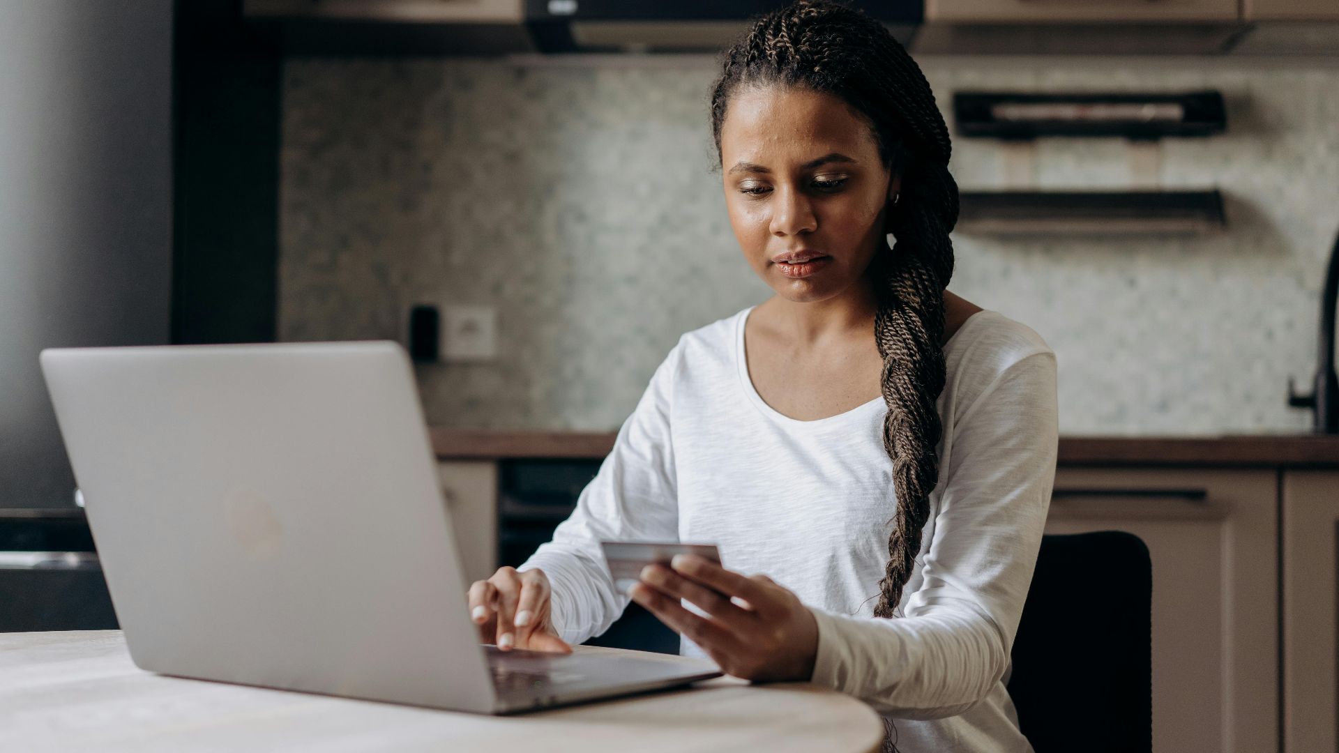 African American woman using laptop and credit card for online shopping at home.