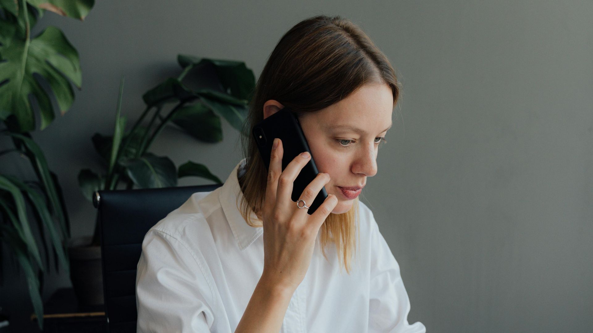 Focused woman architect discussing floor plans on the phone in an office setting.