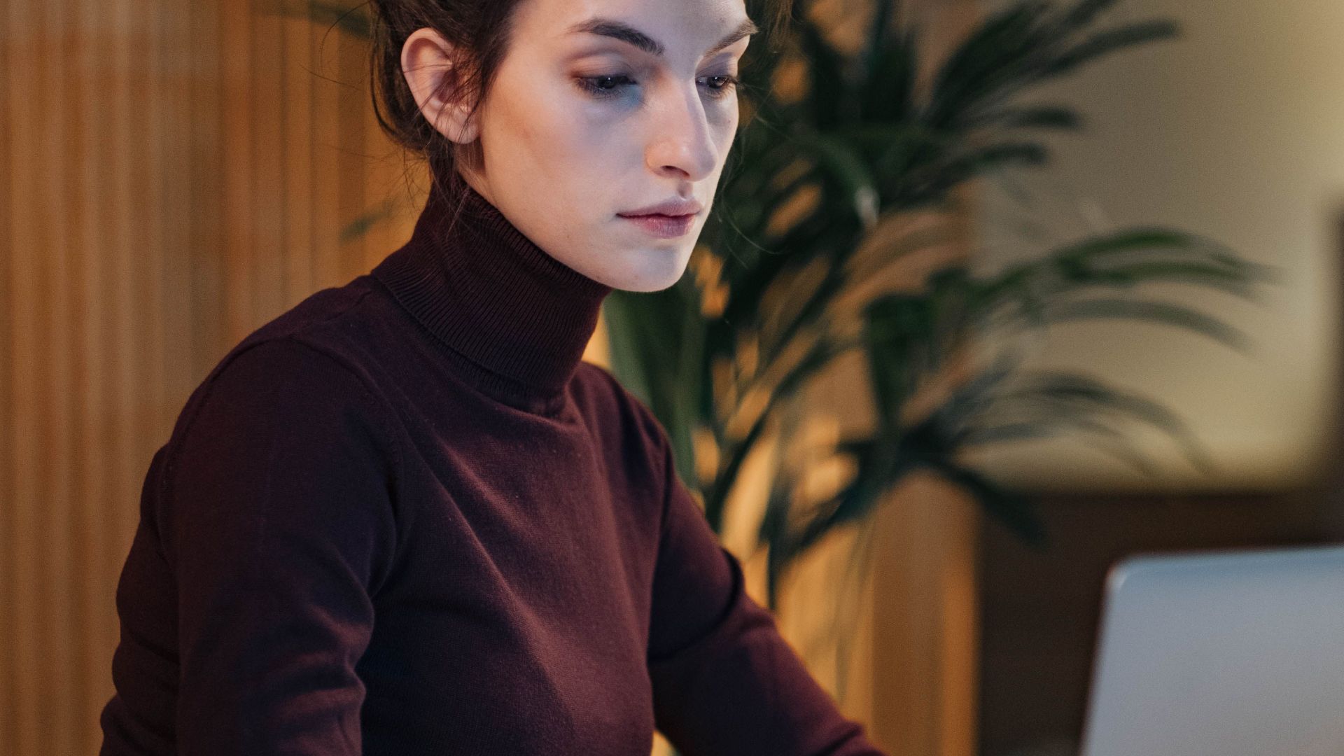 Confident woman using laptop in a stylish office setting. Perfect for business and technology themes.