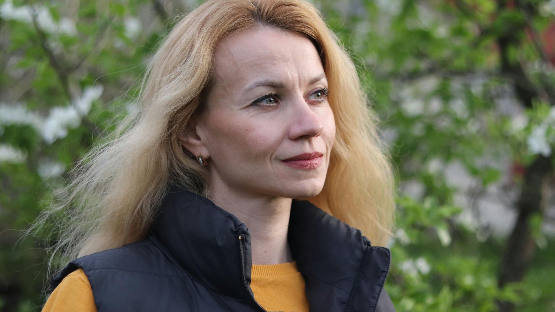 Close-up of a woman in a puffer vest enjoying nature in spring.