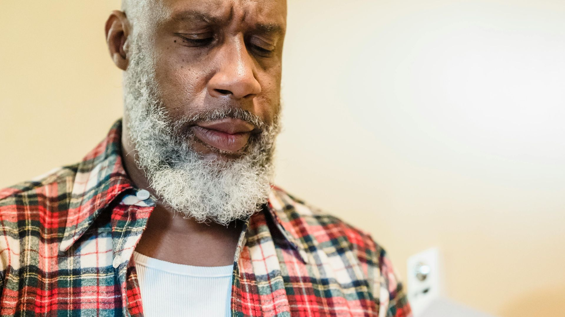 A mature man with a beard attentively reading documents indoors in a focused manner.