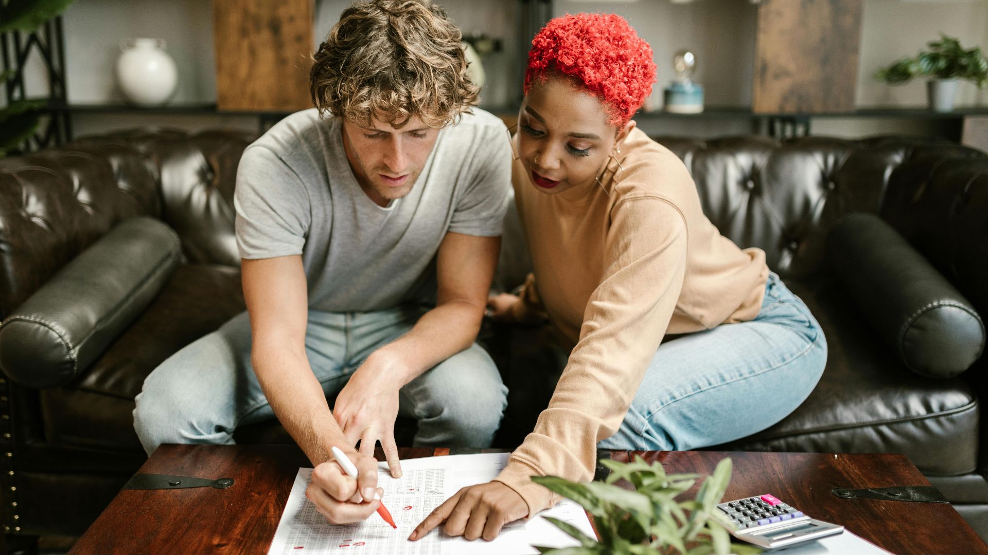 A man and woman collaborating on a project at home, focusing on paperwork.