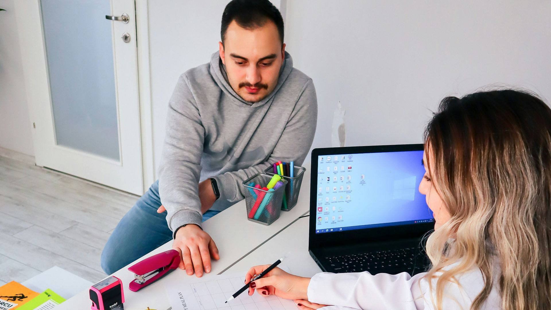a man and a woman sitting at a table with a laptop
