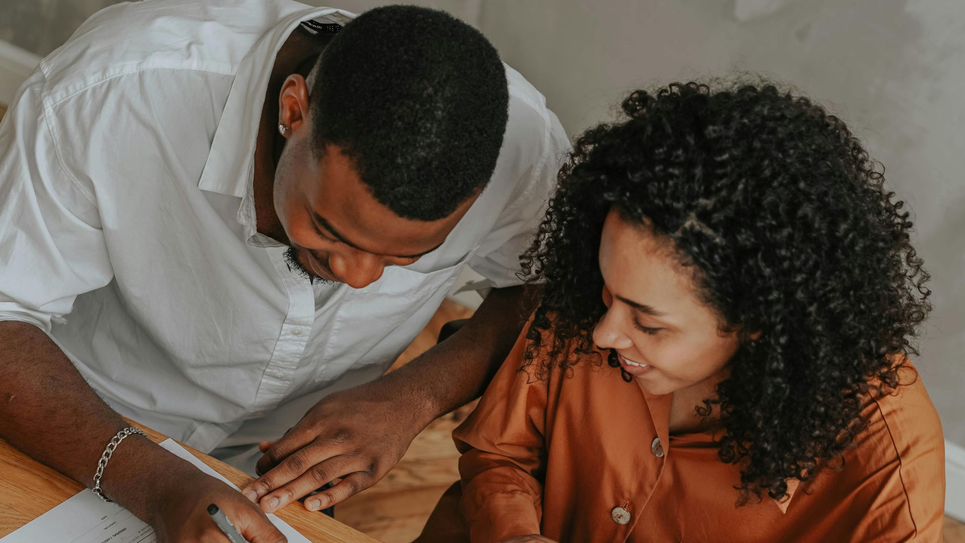 A couple signing an adoption certificate at a table, viewed from above.