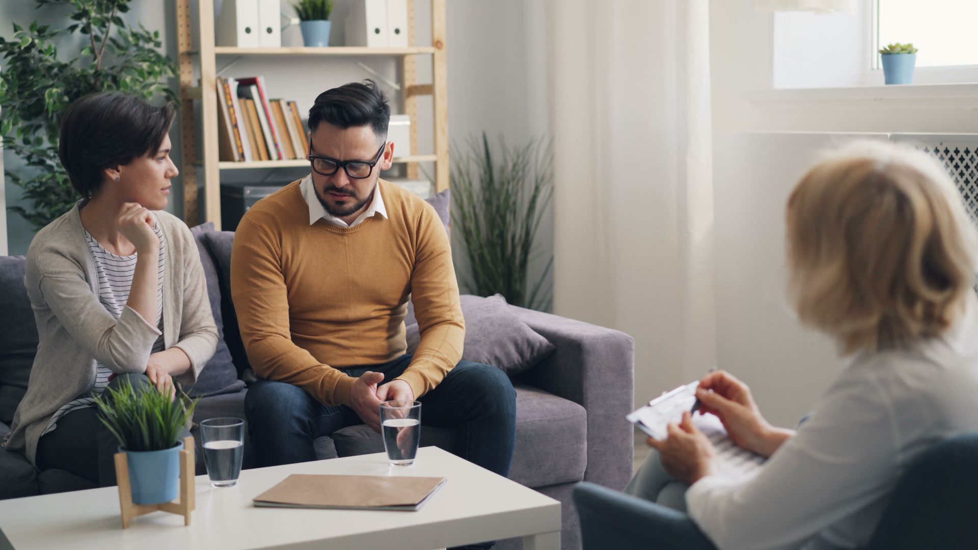 A couple engaged in a counseling session with a therapist in a cozy room.