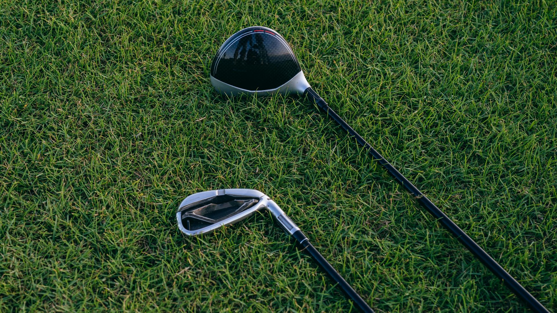 A close-up view of two golf clubs resting on neatly manicured grass, perfect for golf enthusiasts.