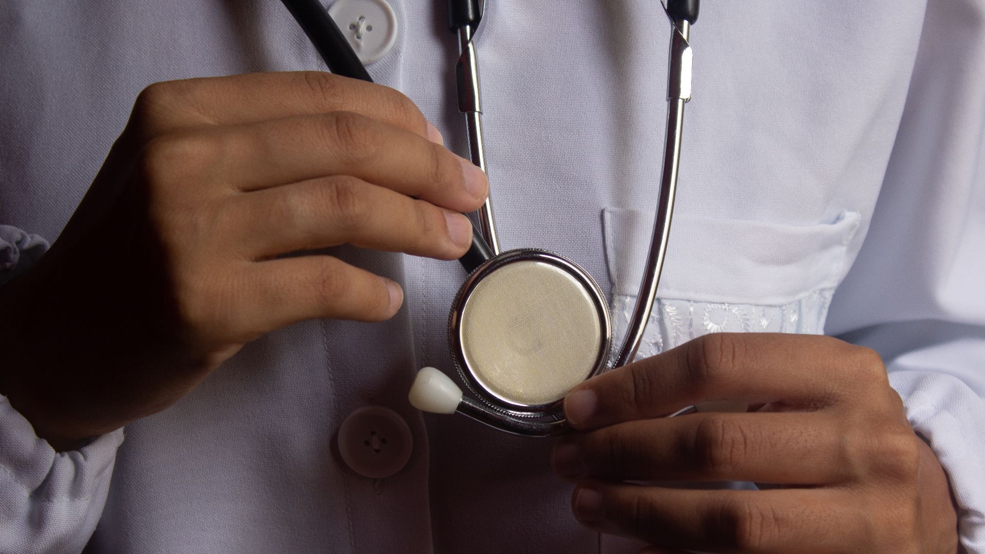 A close-up image showing a doctor holding a stethoscope, symbolizing healthcare and medical practice.