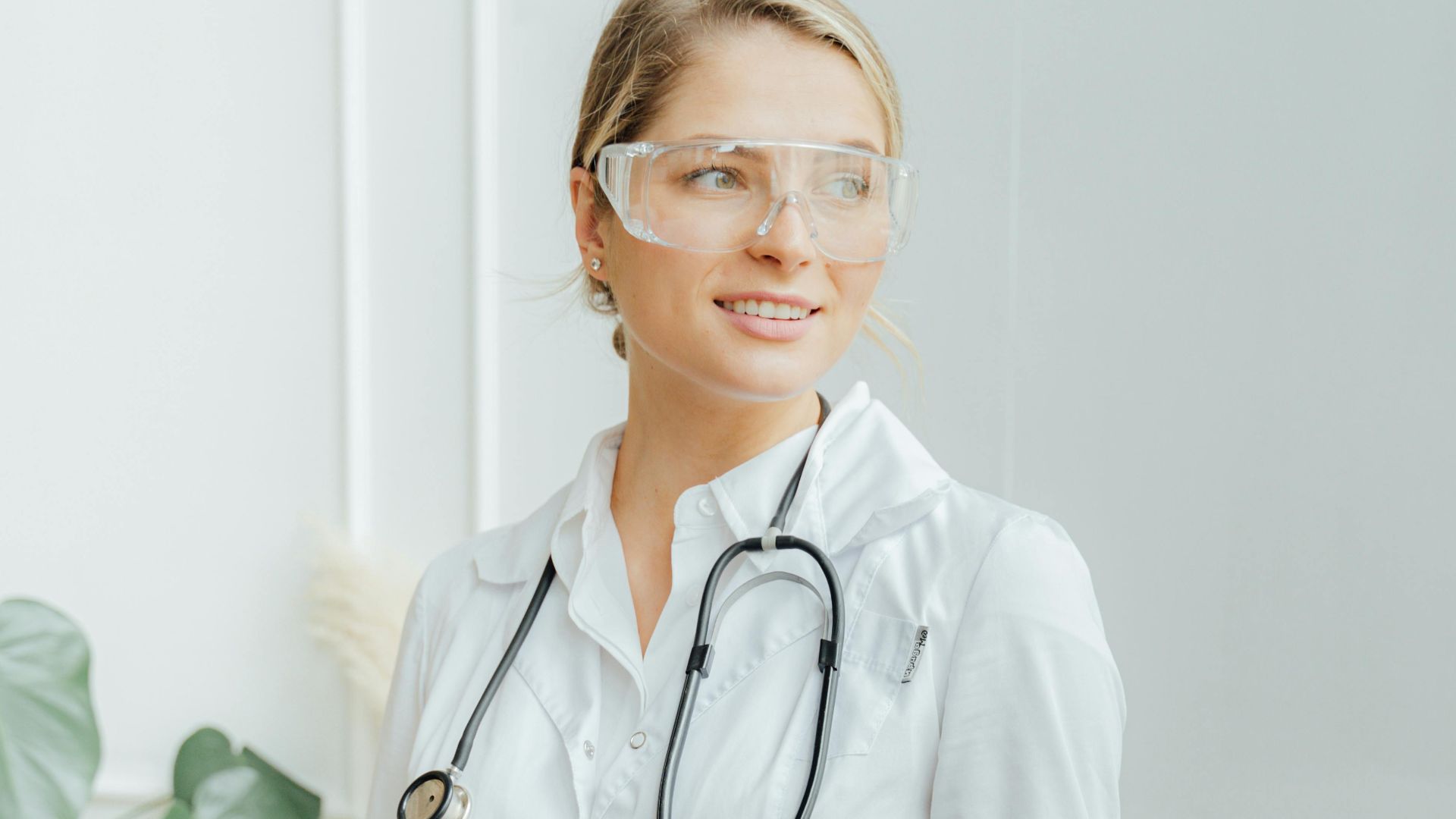 Female doctor wearing goggles and gloves in a clinical setting, showcasing professionalism and care.
