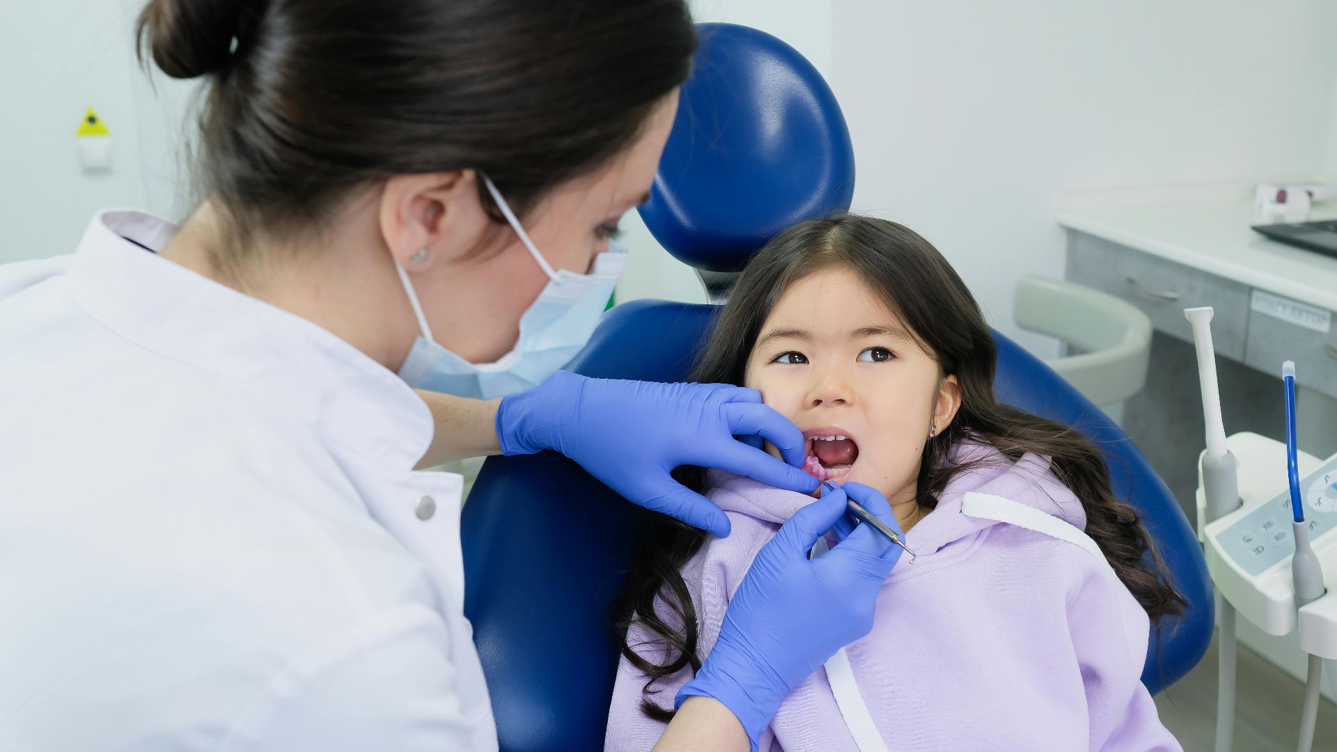 Young girl receives dental checkup from a female dentist in a clinic.