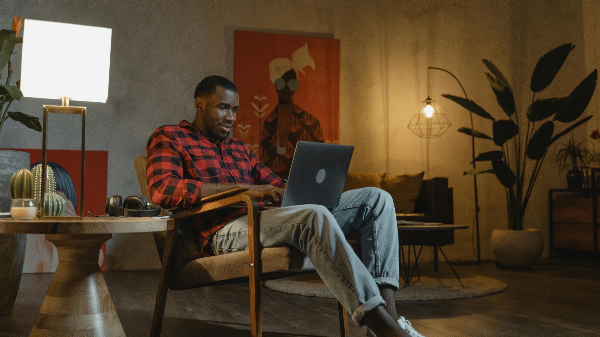 Man working from home on laptop in a stylish and cozy living room setting, embodying modern lifestyle.
