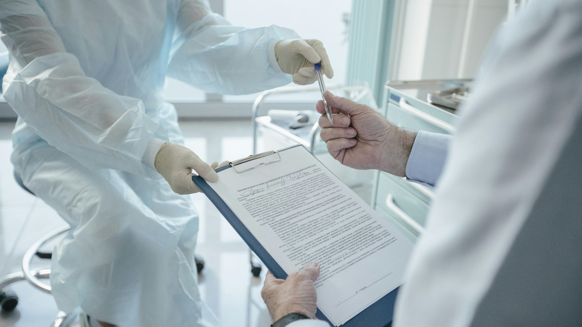 A doctor hands a clipboard to a patient for signature, highlighting medical professionalism.