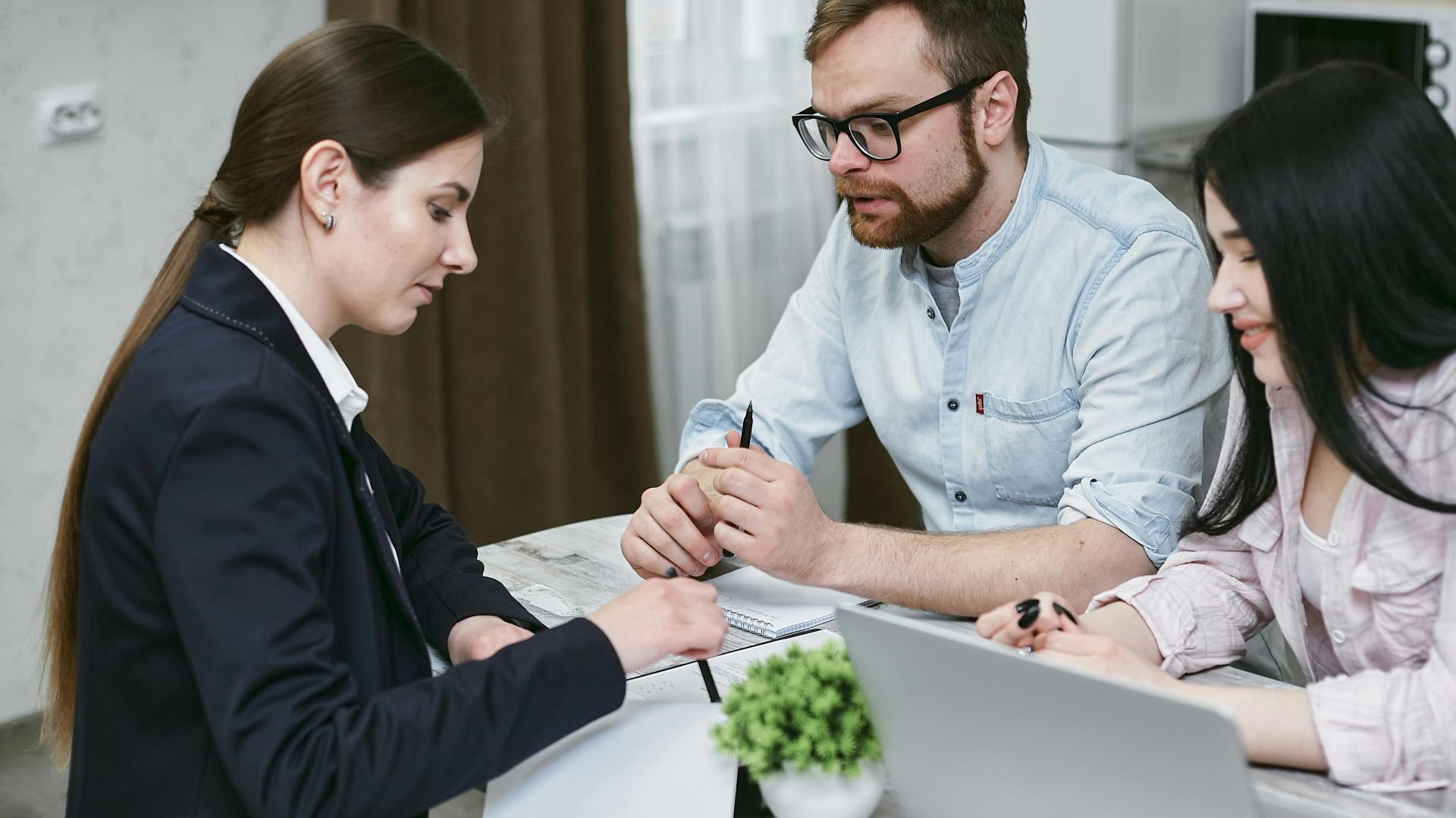 A couple discusses financial documents with their advisor, highlighting investment strategies.