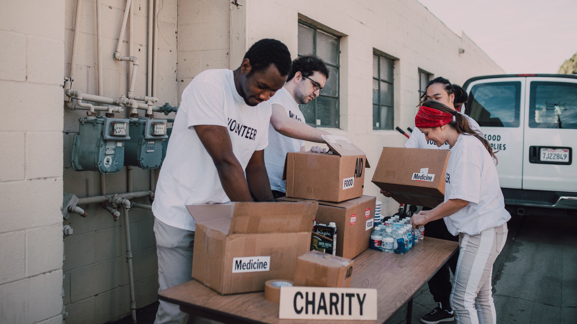 Volunteers sort and prepare donations outdoors for a charitable event.