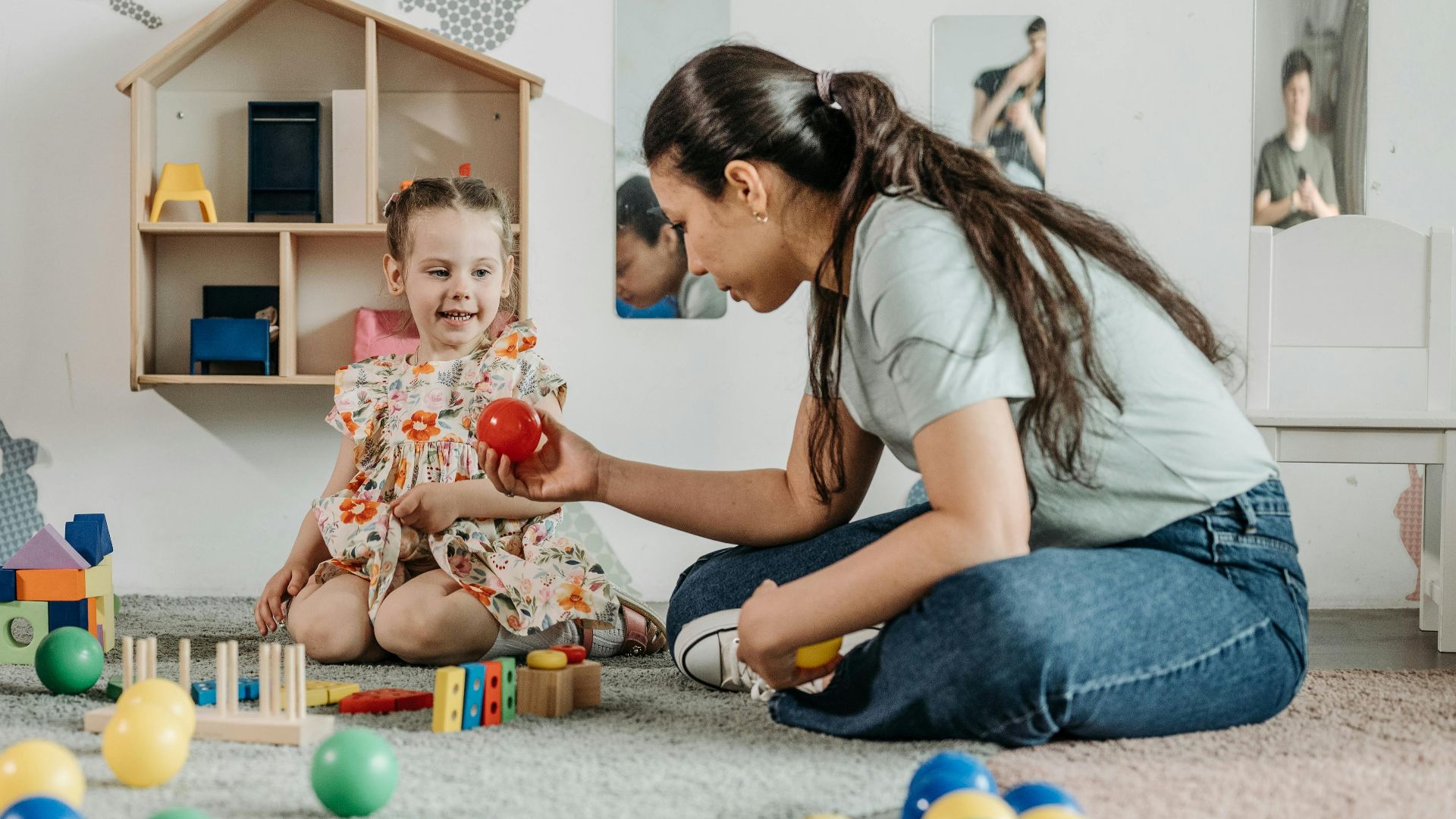 A young girl and woman engaging in an educational play session in a cozy preschool setting.
