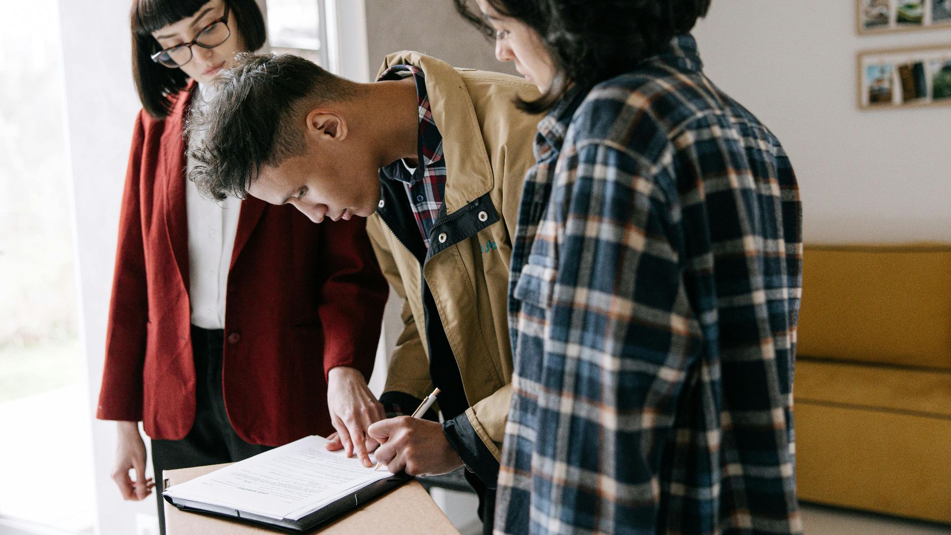 Young couple signing a real estate agreement with an agent indoors.