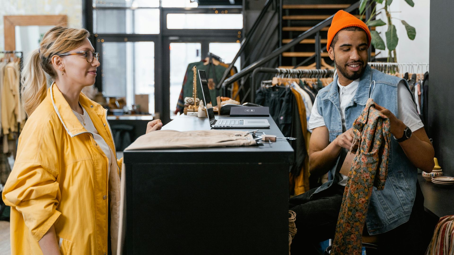 Two young adults interacting at a fashionable boutique, emphasizing style and shopping.