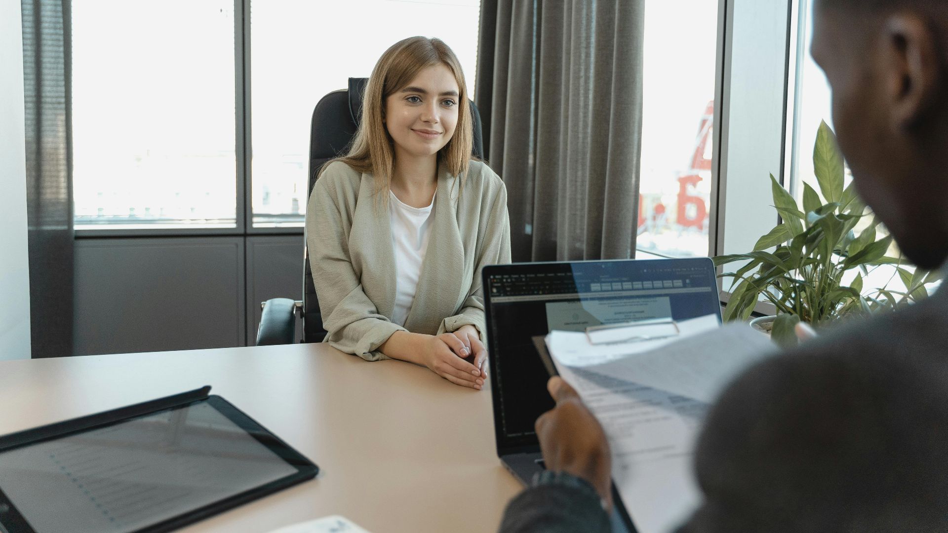 Young woman sitting confidently in a modern office for a job interview.