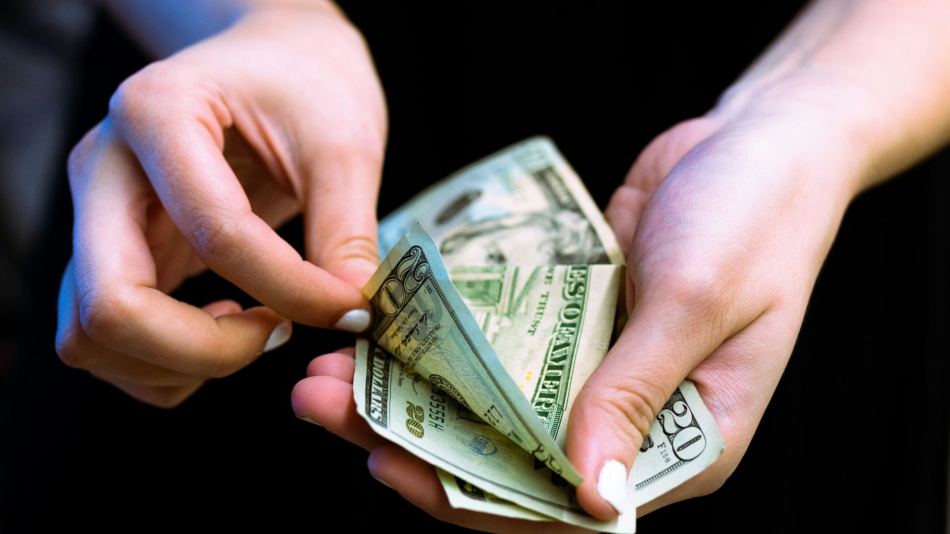 person holding fan of 100 us dollar bill