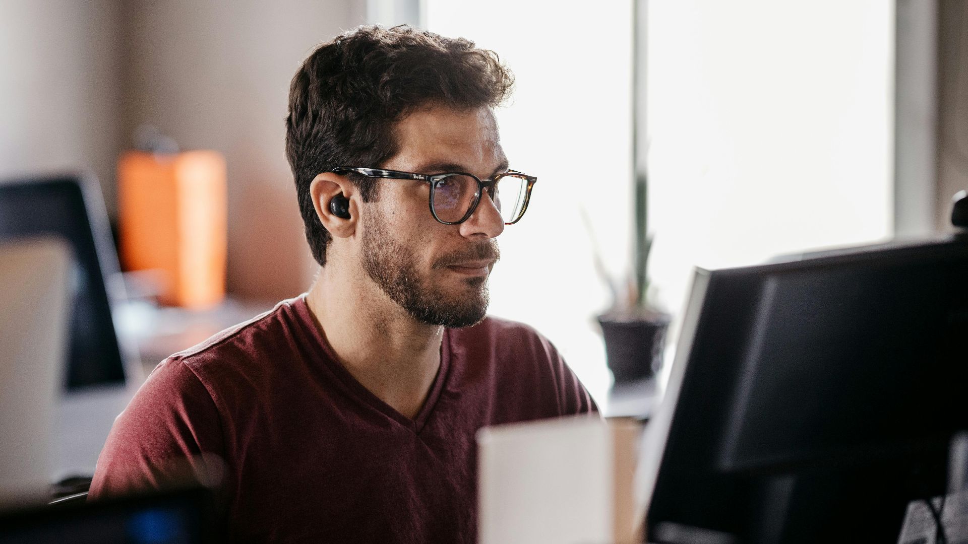 Man in eyeglasses concentrating on computer screen in modern office