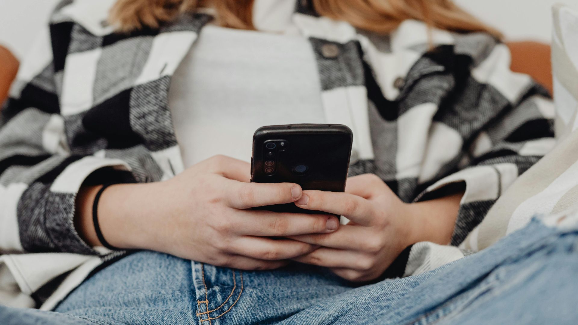 Young woman in casual wear using a smartphone indoors, emphasizing connection and technology.