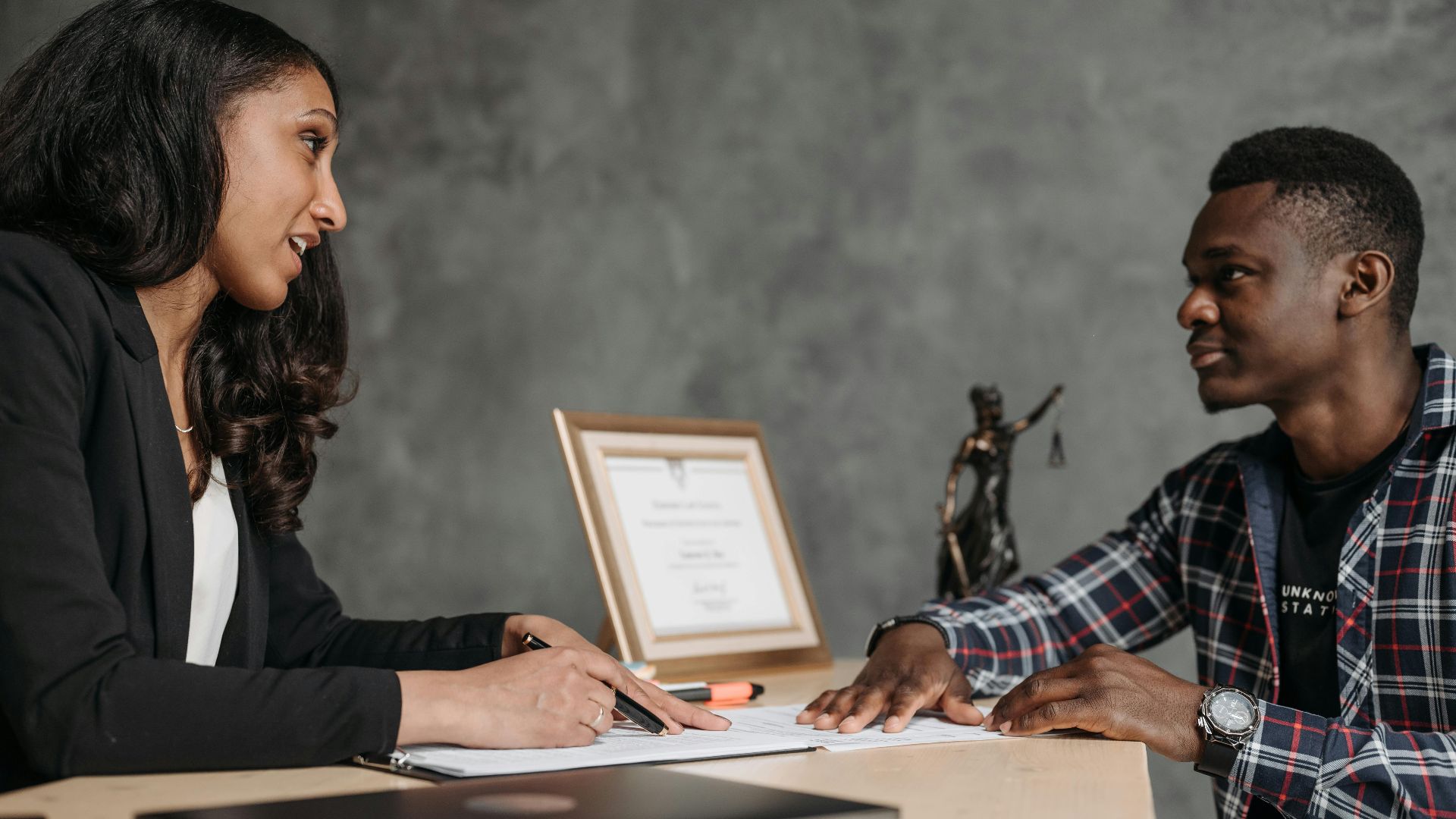 Two adults engaging in a professional conversation at an office desk, showcasing collaboration.