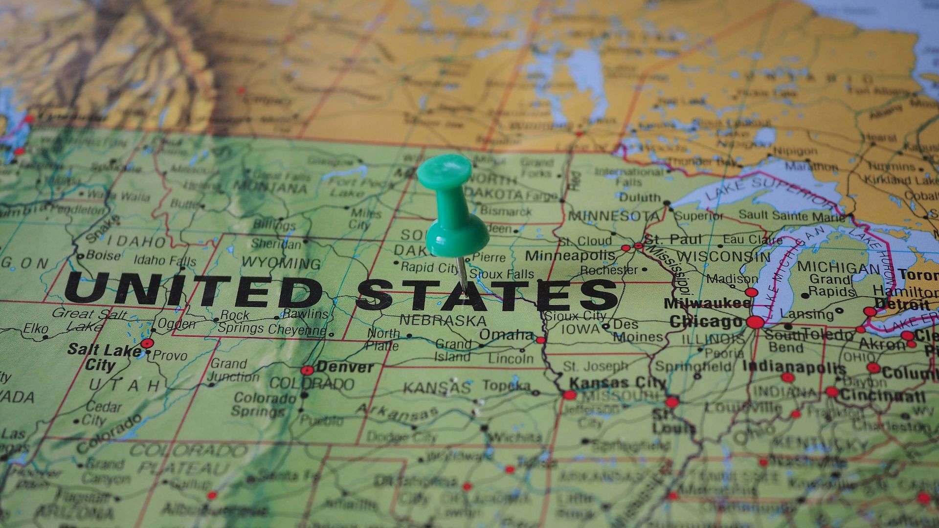 High-angle view of a map featuring the United States with a green pin indicating a specific location.