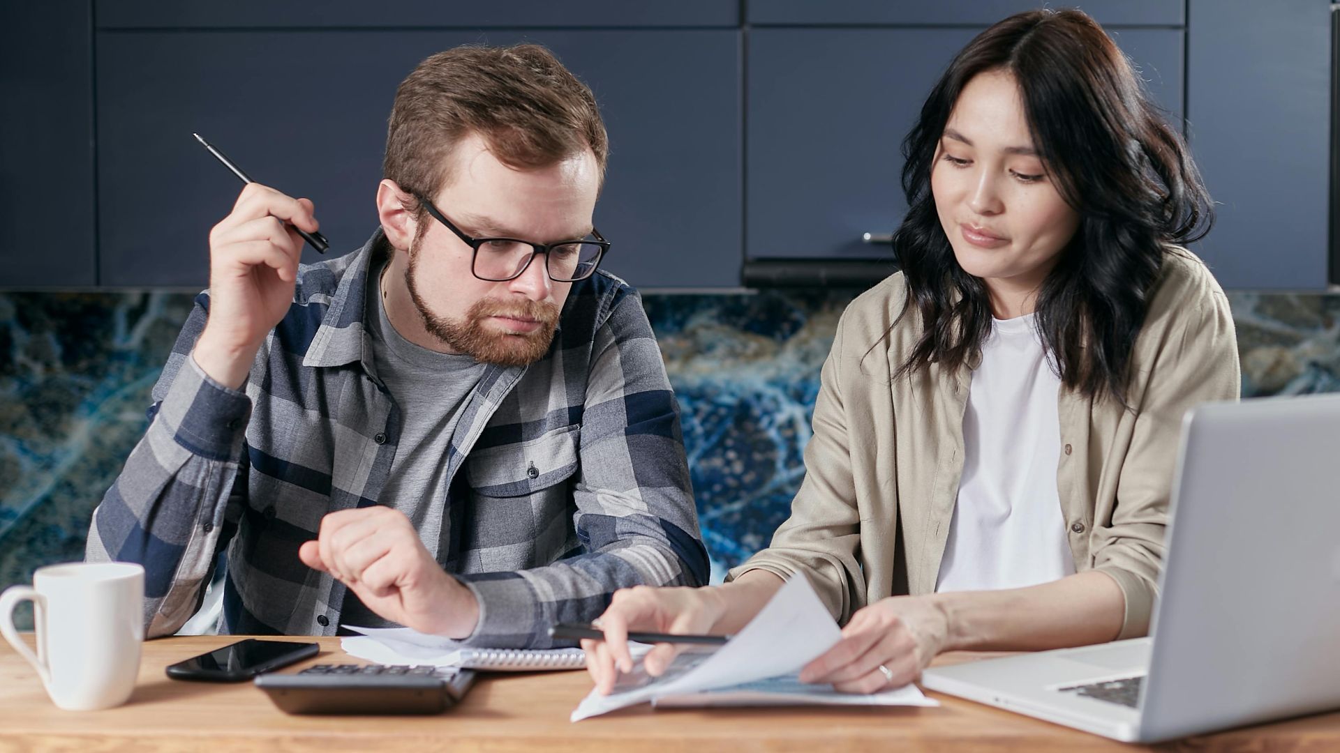 A couple is reviewing and calculating their household bills together at home.