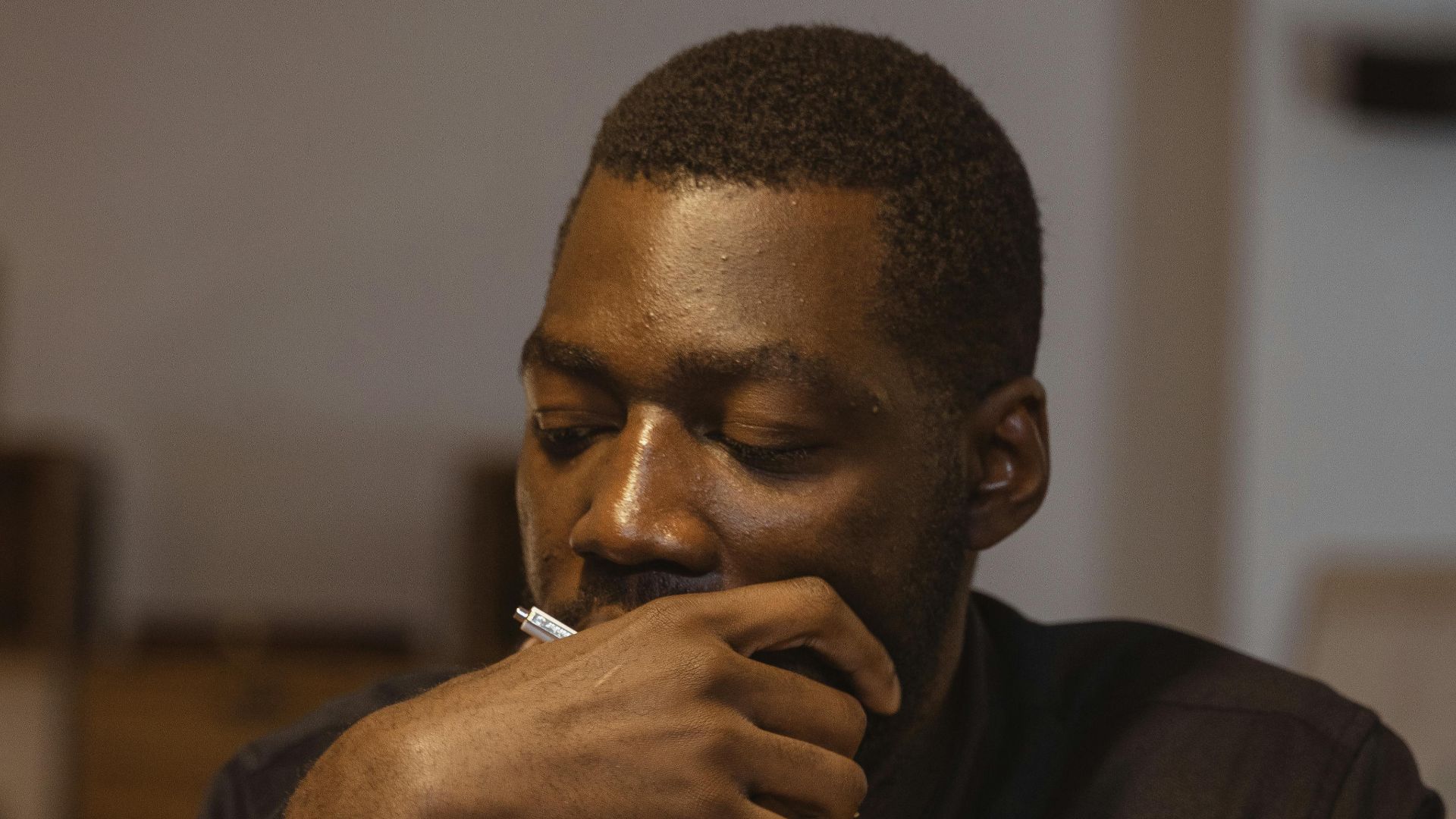 A thoughtful black businessman focusing on paperwork in an office setting.