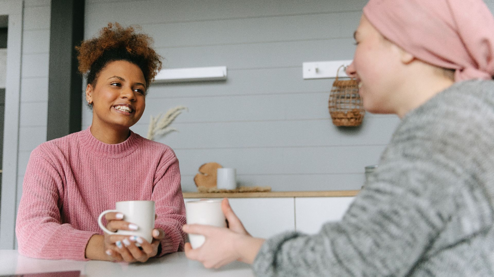 Two women share a joyful coffee moment at home, embodying friendship and warmth.
