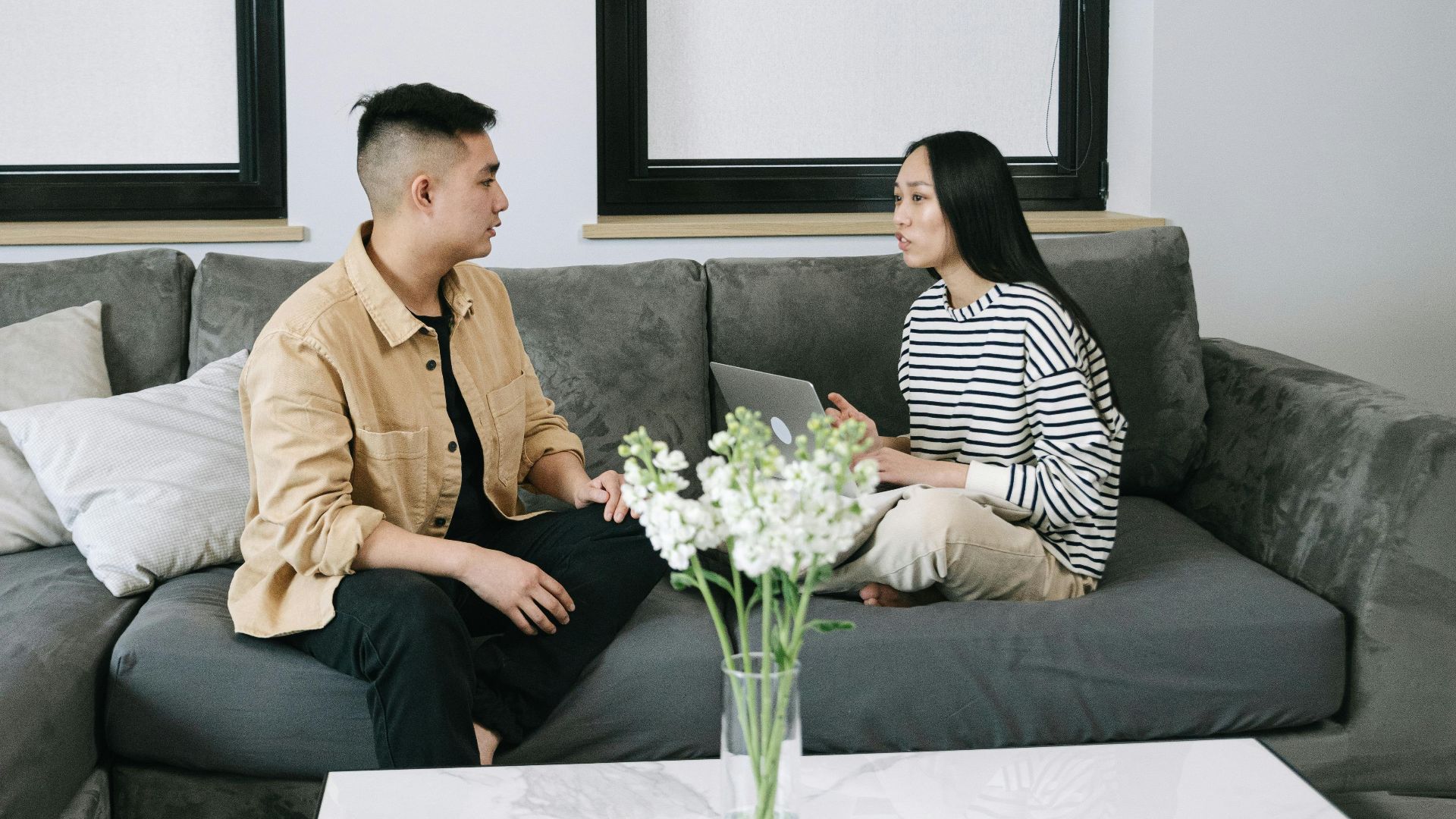 A man and woman having a relaxed conversation indoors on a stylish sofa.