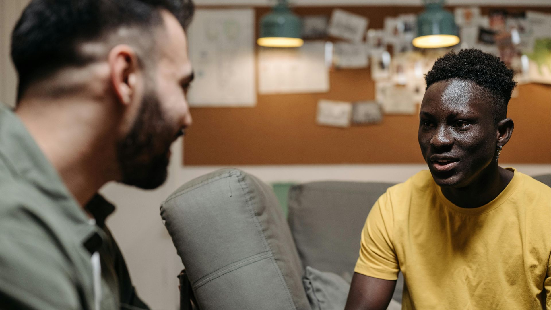Two men having a casual conversation in a cozy, indoor setting with a warm atmosphere.
