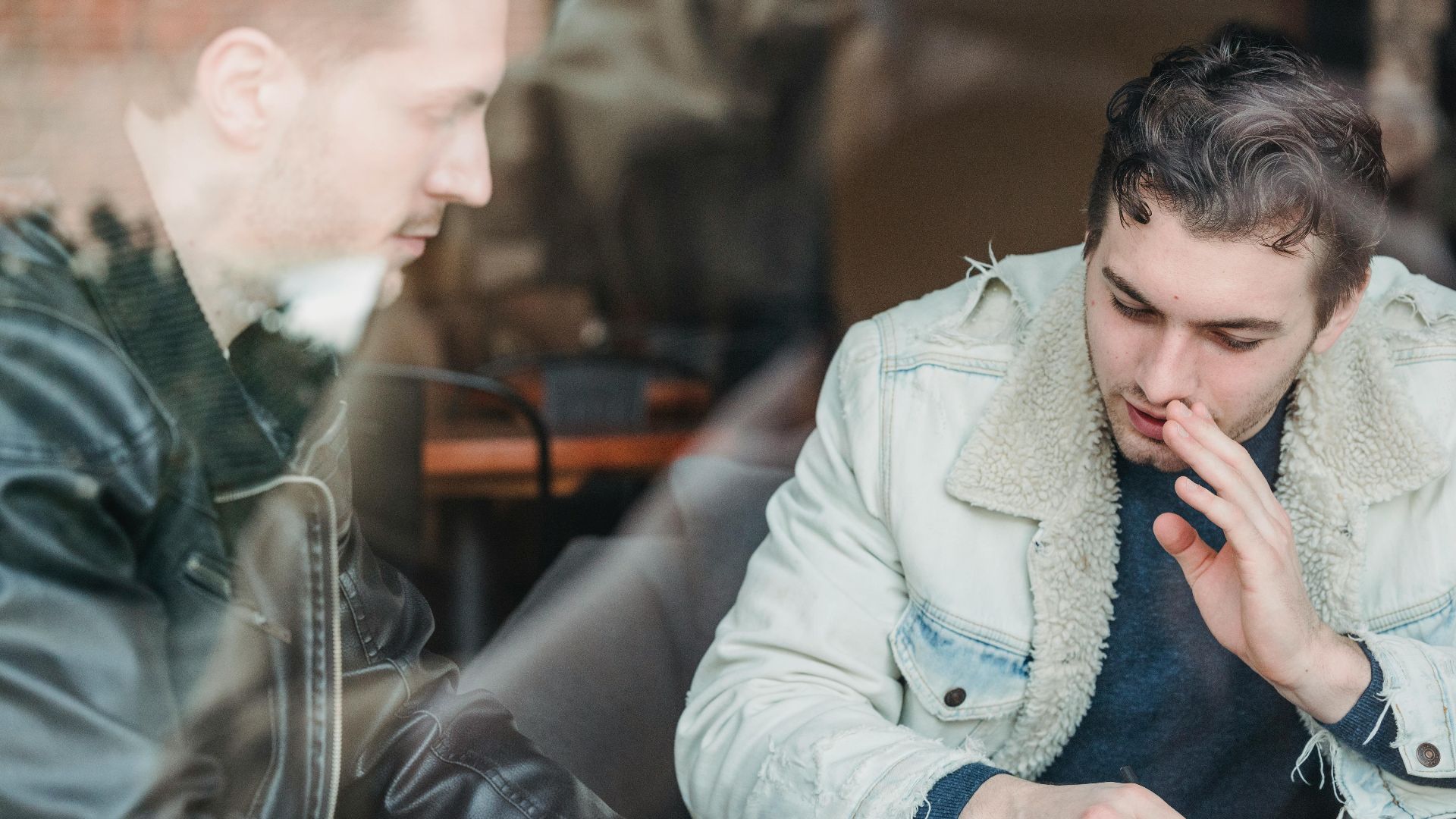 Through glass of business partners in casual wear talking about business strategy while working in cafe
