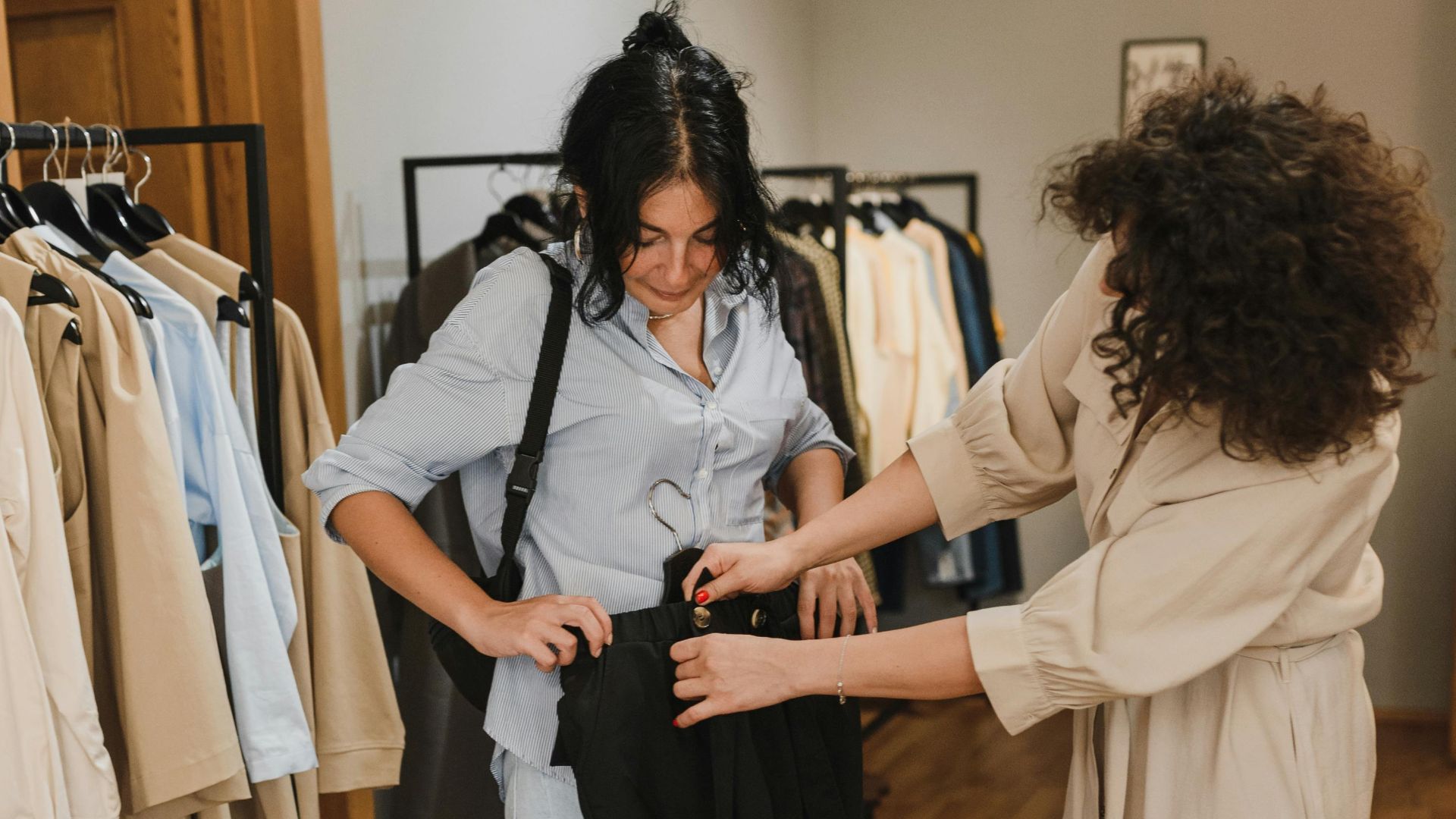 Fashion shop interior with customer and saleswoman interacting over clothes shopping.