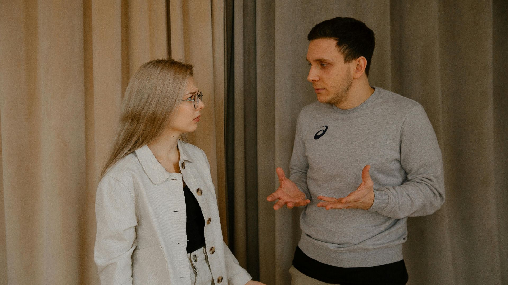 A young couple passionately discussing indoors, capturing intense emotions and gestures.