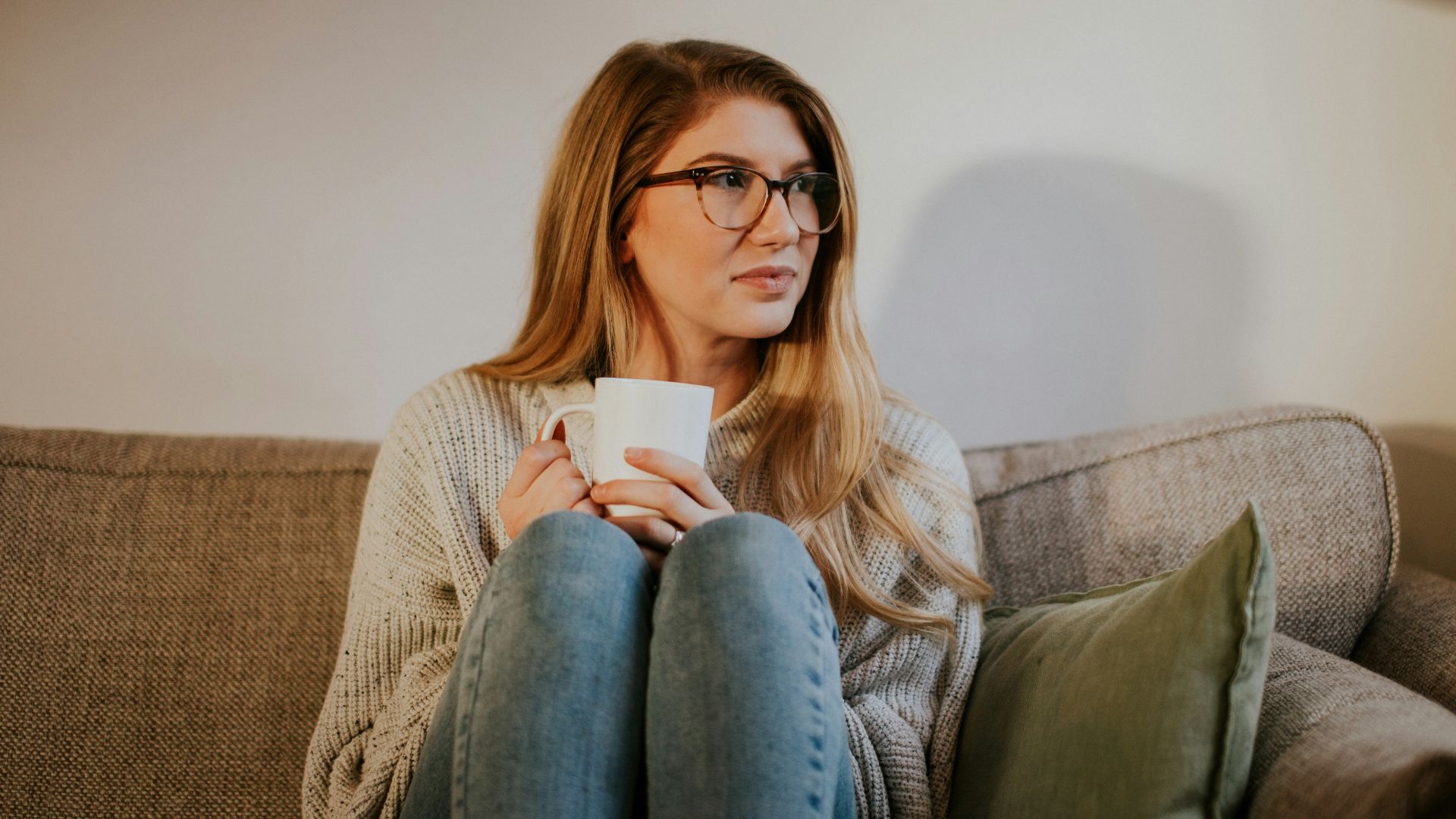 woman in blue denim jeans sitting on gray sofa