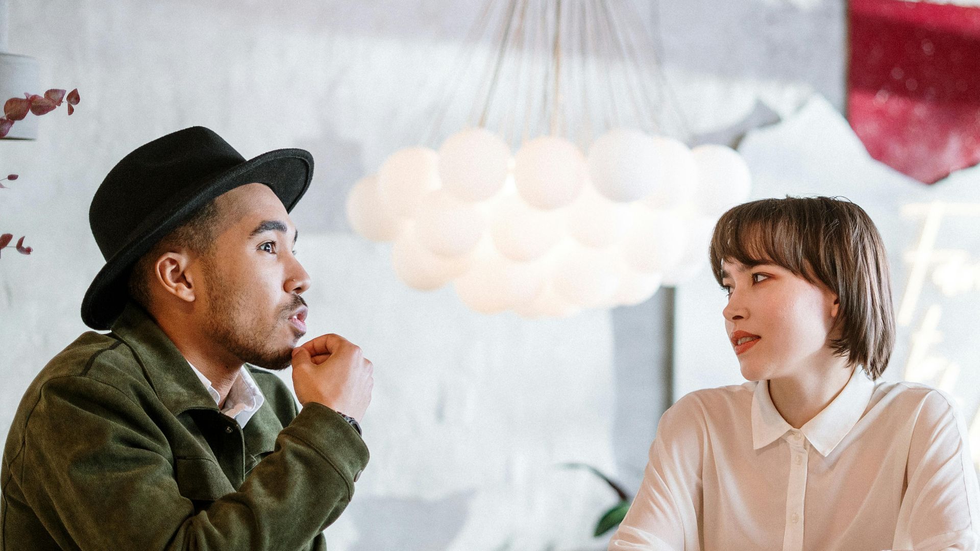 Two adults engage in a casual conversation in a stylish indoor café environment.