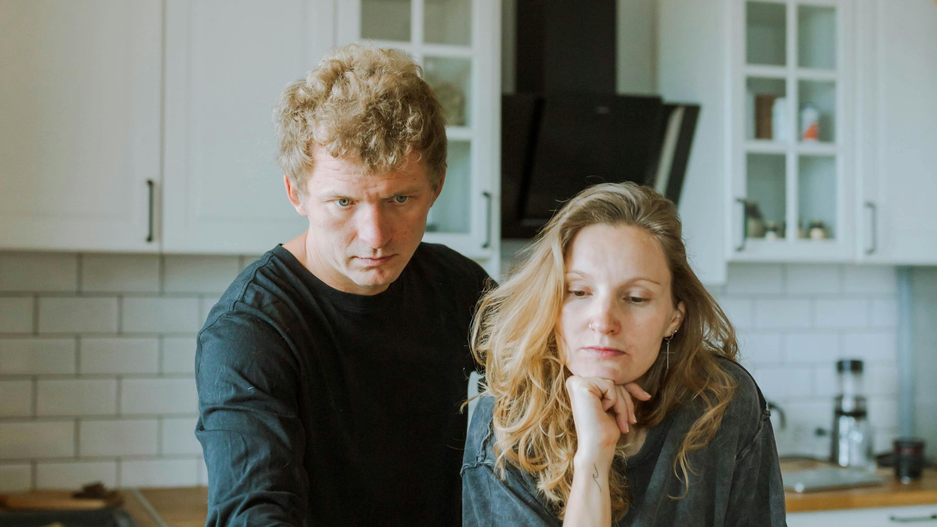 Man and woman focused on laptop work in a bright, modern kitchen setting.