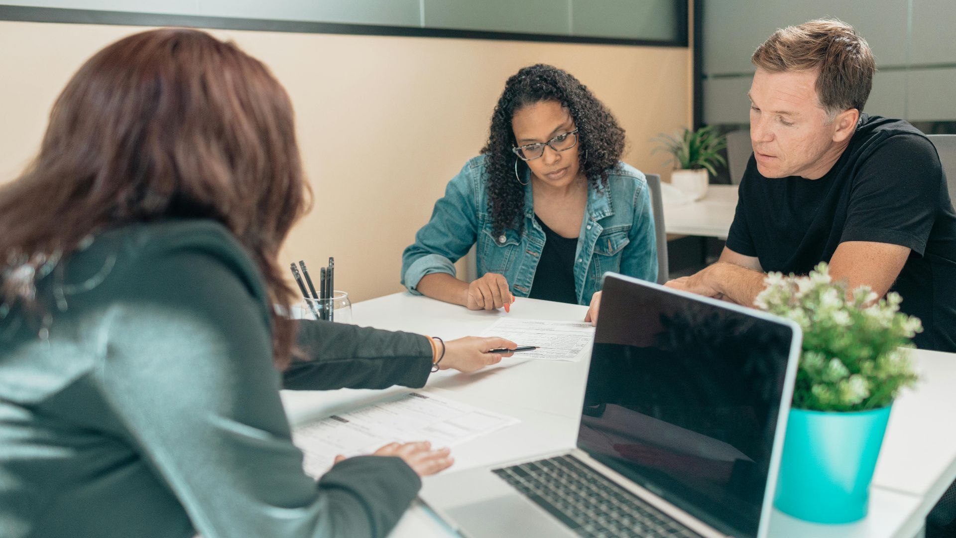 Couple meeting with advisor for adoption process in a modern office setting.