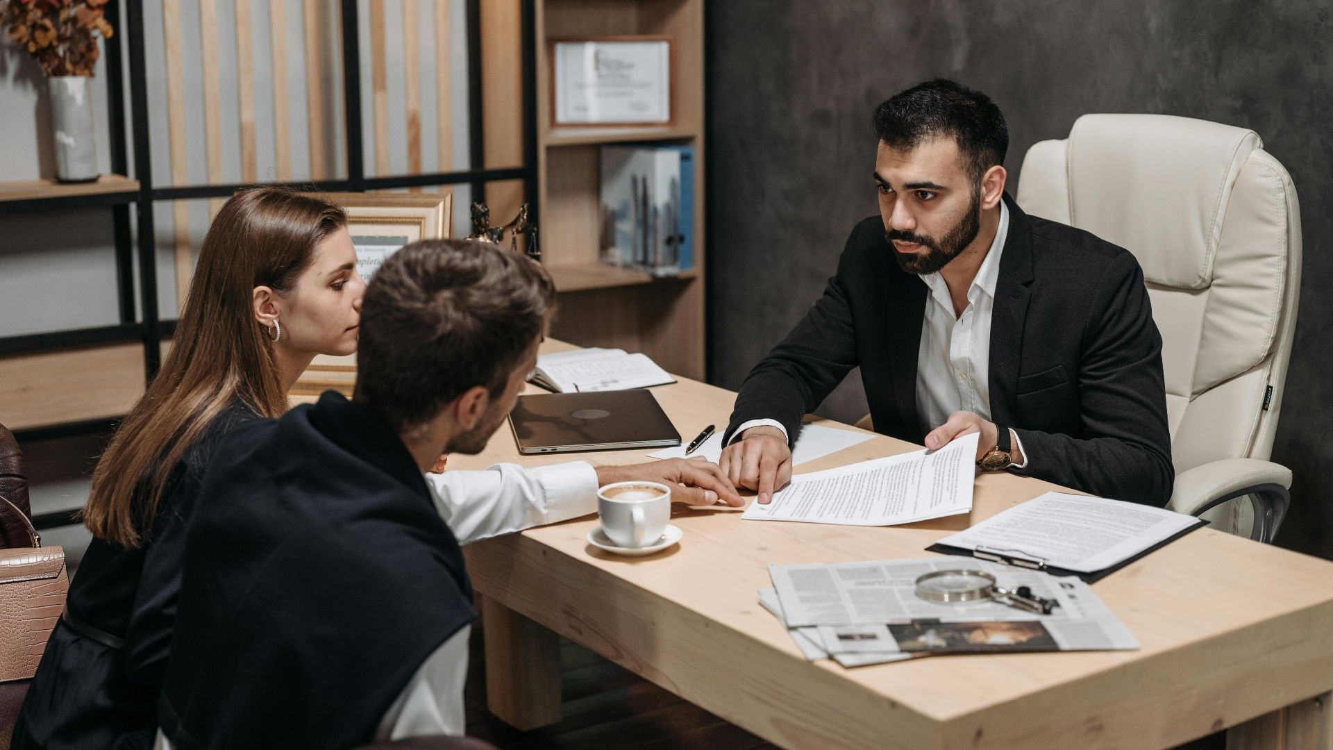 Lawyer discussing legal documents with clients at office desk.