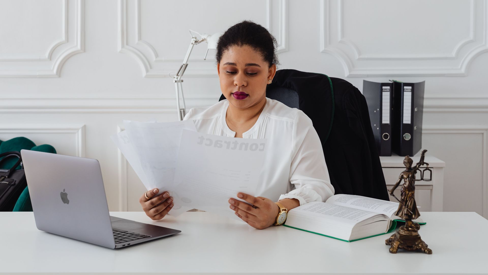 Confident businesswoman analyzing contracts at her clean, organized desk.