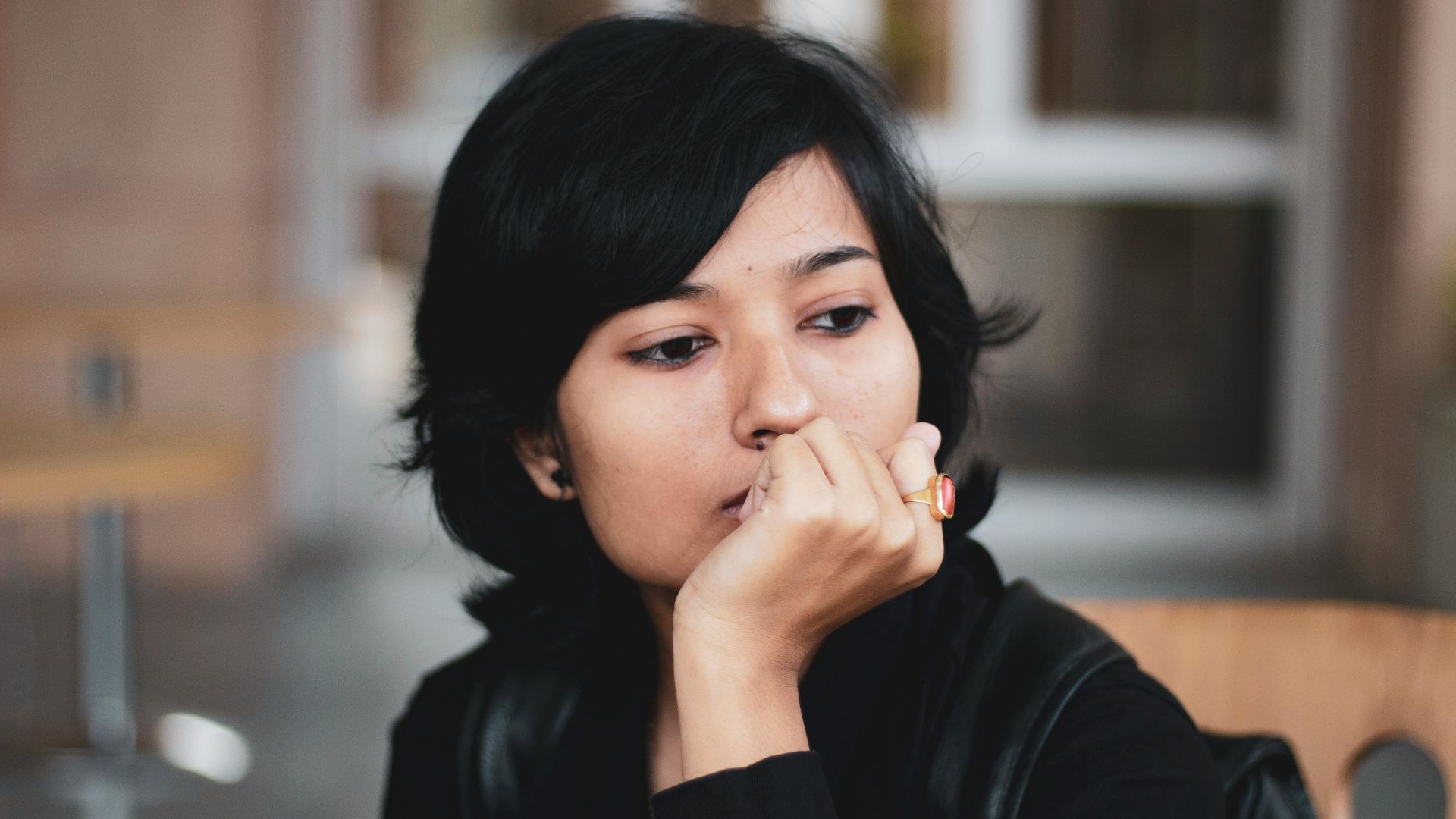 Portrait of a thoughtful woman indoors, lost in contemplation.