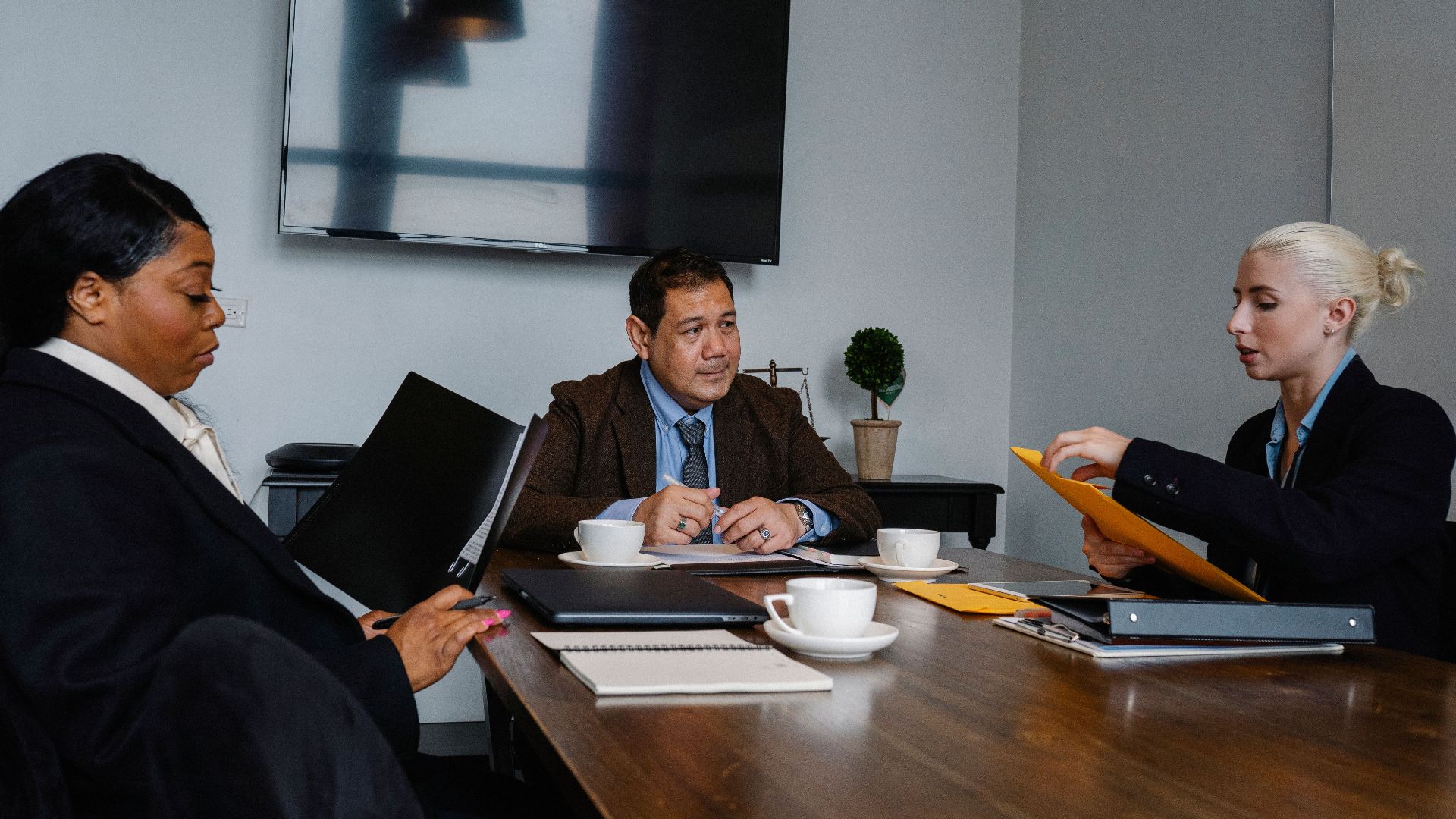 Group of multiethnic coworkers in formal wear sitting at table with documents and discussing strategy of project