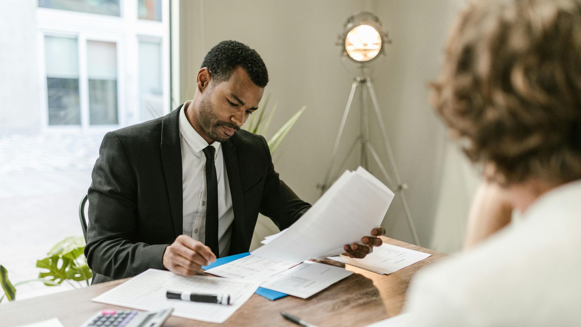 Professional businessman reviewing documents at a desk in a modern office setting.
