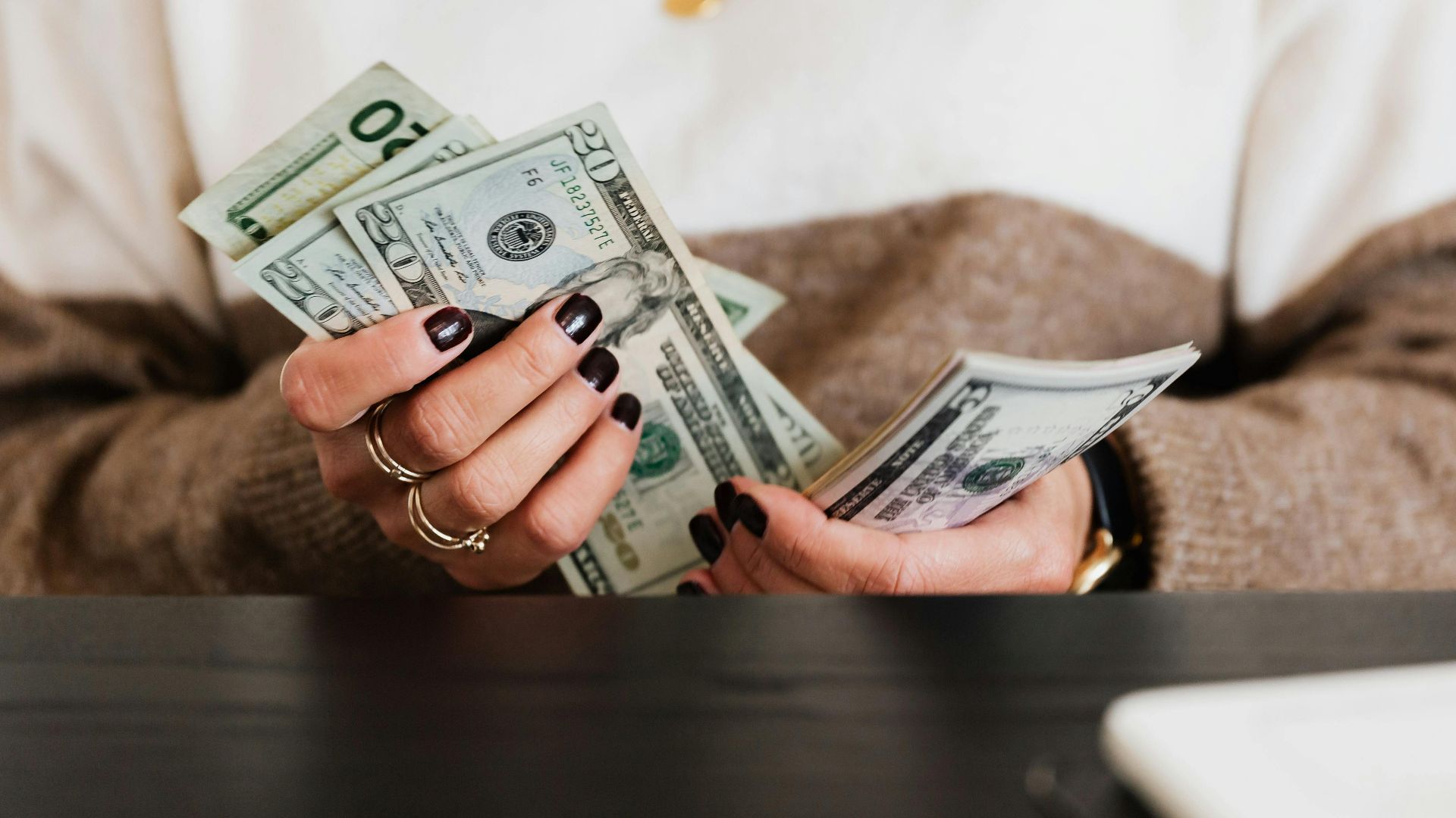 Close-up of hands counting US dollar bills, depicting finance and money handling.