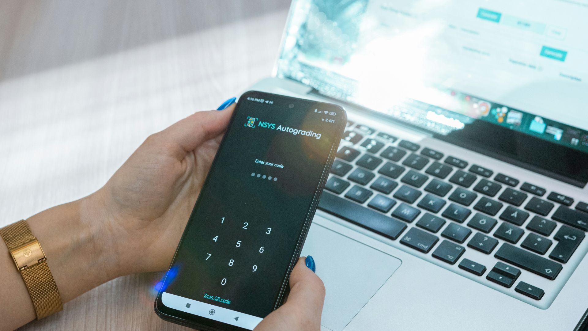 a person holding a cell phone in front of a laptop
