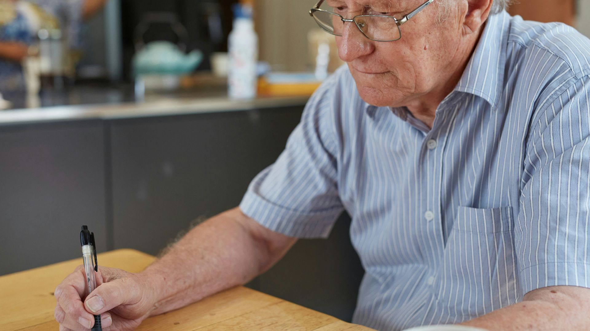 a man sitting at a table writing on a piece of paper